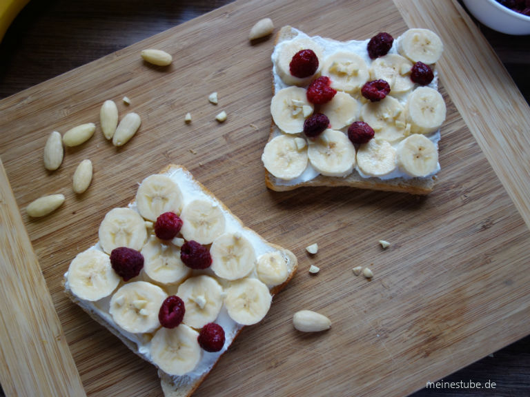 Bananen-Toast mit Joghurt oder Frischkäse belegt mit Himbeeren und mandelstücke